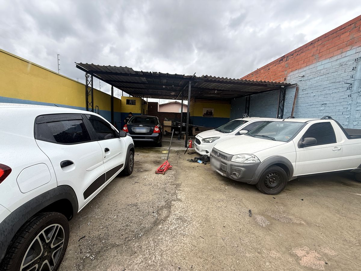 Pátio da oficina com veículos estacionados sob e diante da cobertura